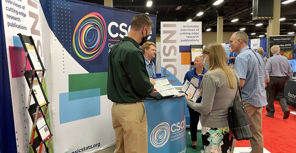 Anthony Greiter, learning and development specialist, (front, left) talks with a conference attendee at the CSAFE booth during the 2021 IAI Conference. Also pictured are CSAFE researchers Seth Pierre (back left) and Alexandra Arabio (back, center).