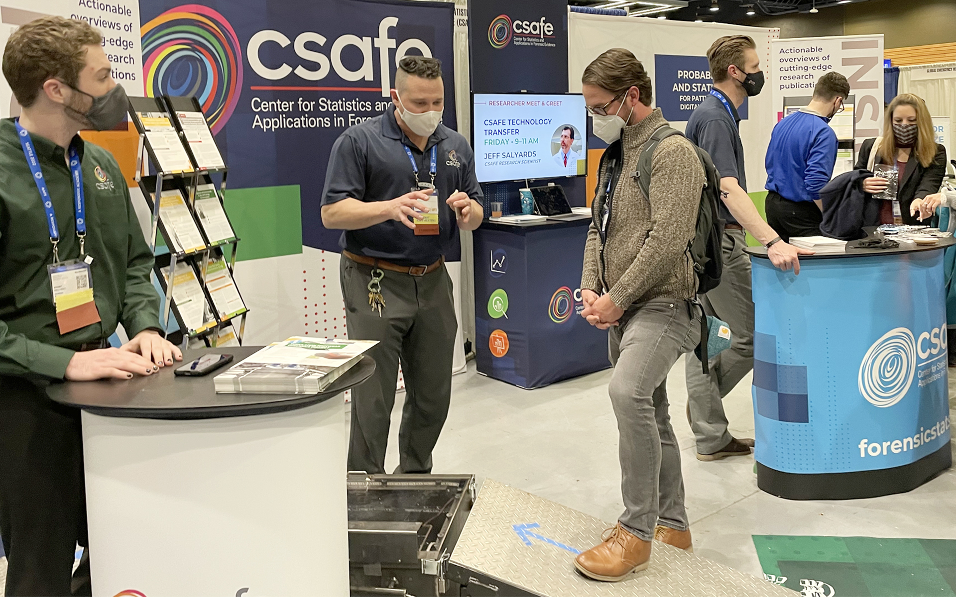Richard Stone (center) talks with a conference attendee about the functions of the footwear scanner device.