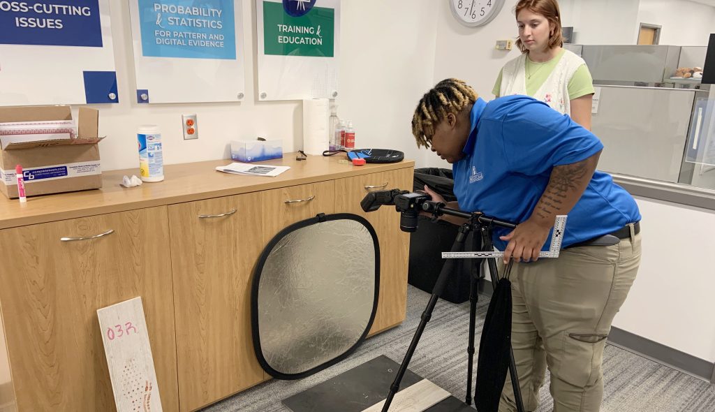 CSAFE REU student intern Saniya Lyles (front) and student mentor Emma Thatcher are setting up a camera to take pictures of mock crime scene shoe impressions.