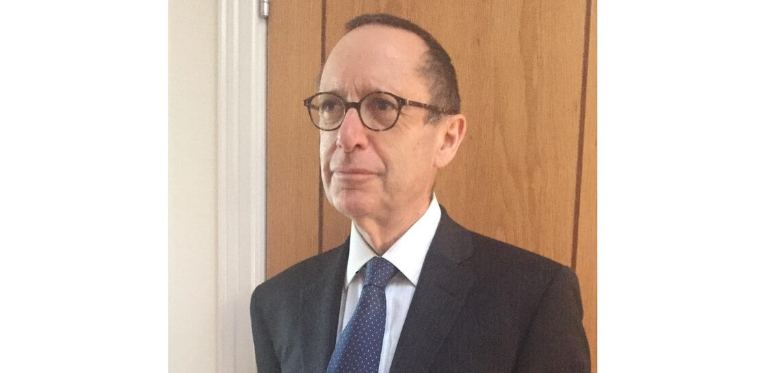 Bernard Silverman stands indoors in front of a wooden door, looking slightly to the side.