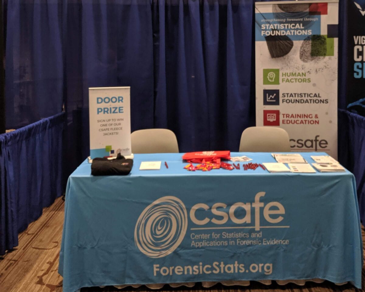 CSAFE booth with blue tablecloth, flyers, pens, and a sign for a door prize at a conference.