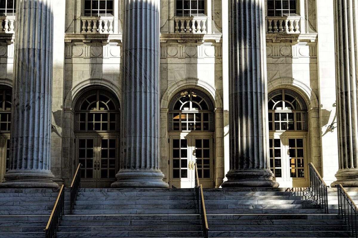 Stone steps and large columns in front of an ornate, classical-style building facade.