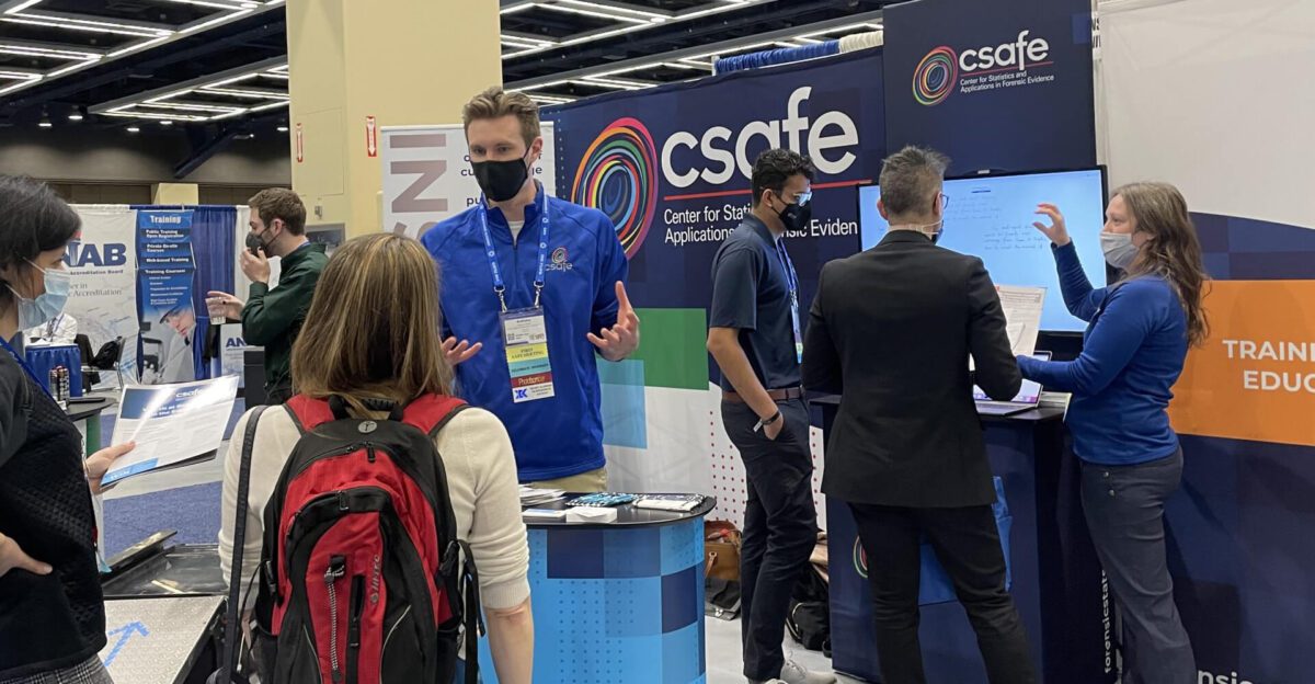 People talking and presenting at a CSAFE booth at a conference or expo.