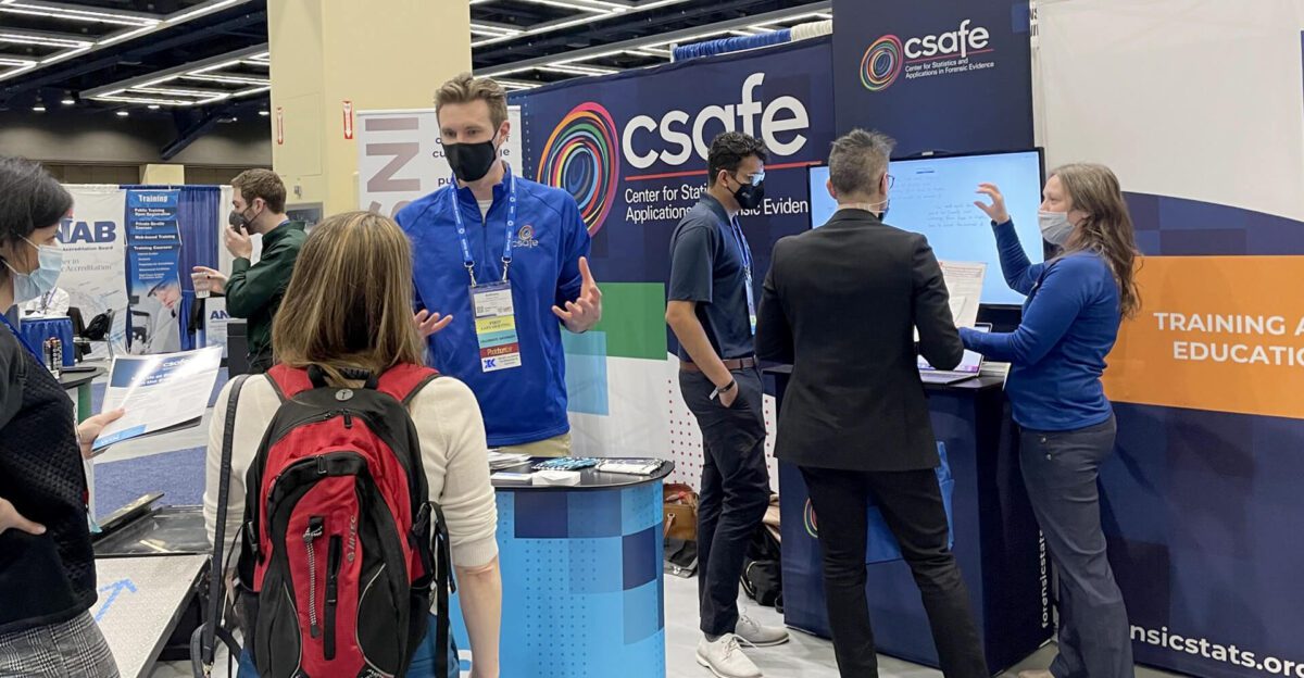 People talking and presenting at a CSAFE booth at a conference or expo.