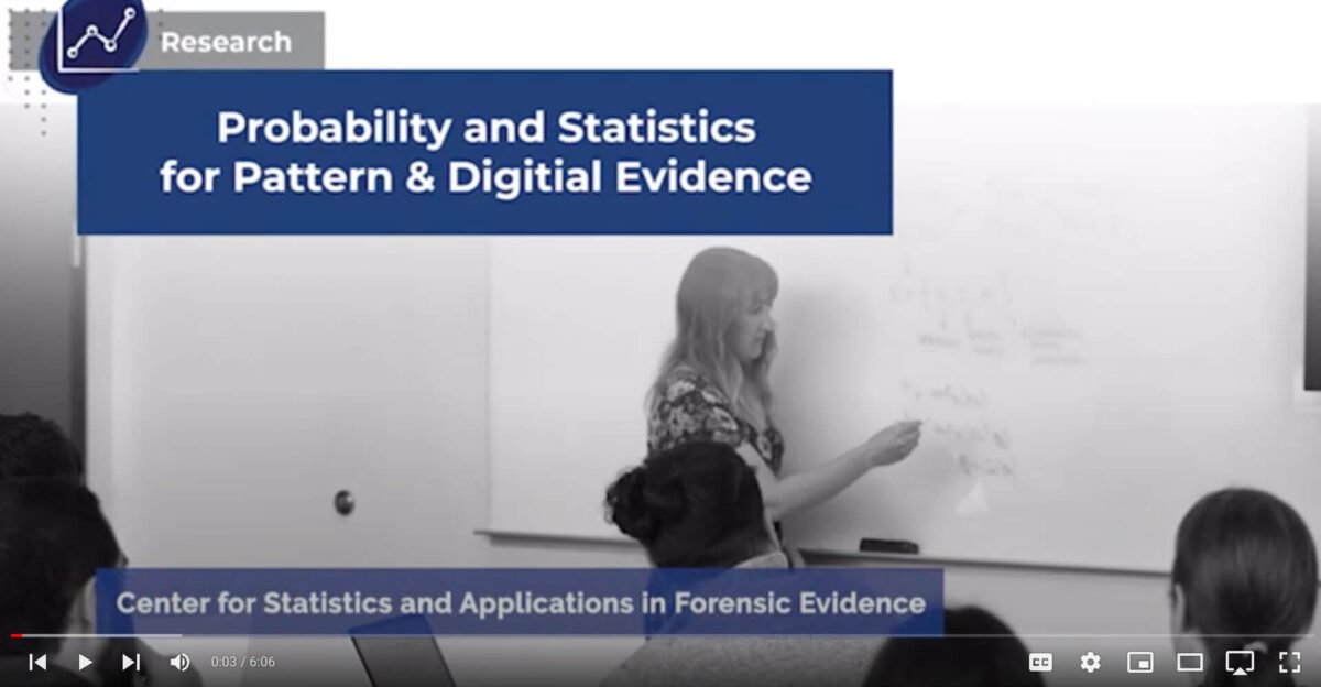 A woman writes on a whiteboard during a lecture on probability, statistics, and digital evidence.