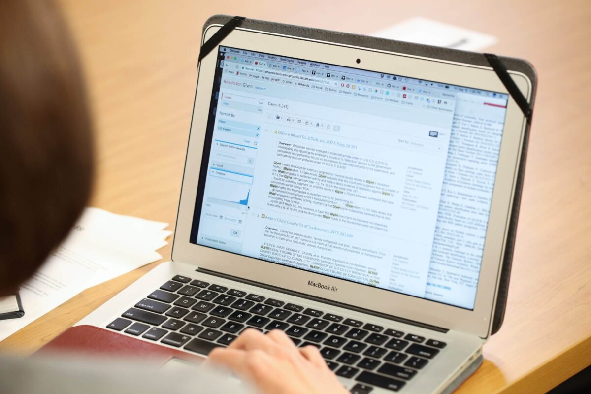 Person using a MacBook Air to search and read case law on an online legal research platform.