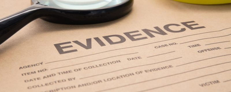 Close-up of an evidence form with a magnifying glass resting on top.