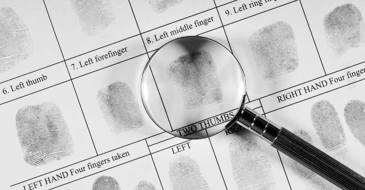 A magnifying glass over fingerprint records on a fingerprint identification sheet.