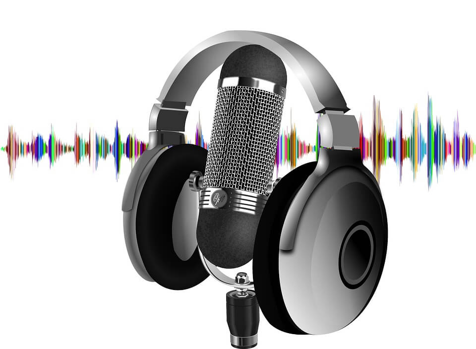 A microphone with headphones and colorful sound waves in the background on a white backdrop.