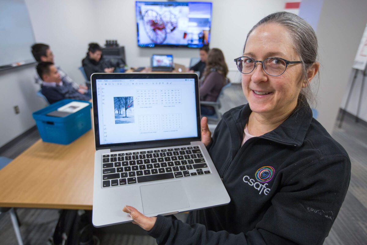 Jennifer Stego holds a laptop with a calendar on screen.