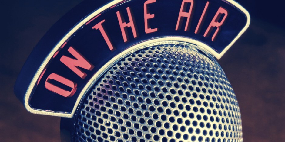 A vintage microphone with a sign above it that reads "ON THE AIR" in bold red letters.