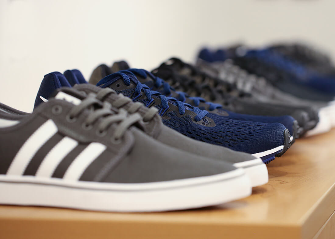 A row of athletic shoes in various colors, lined up on a wooden surface.