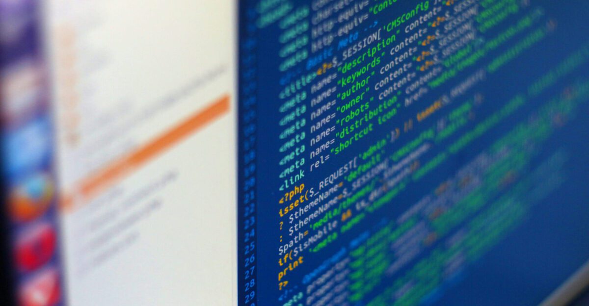 A computer screen displaying colorful lines of code next to a blurred user interface sidebar.