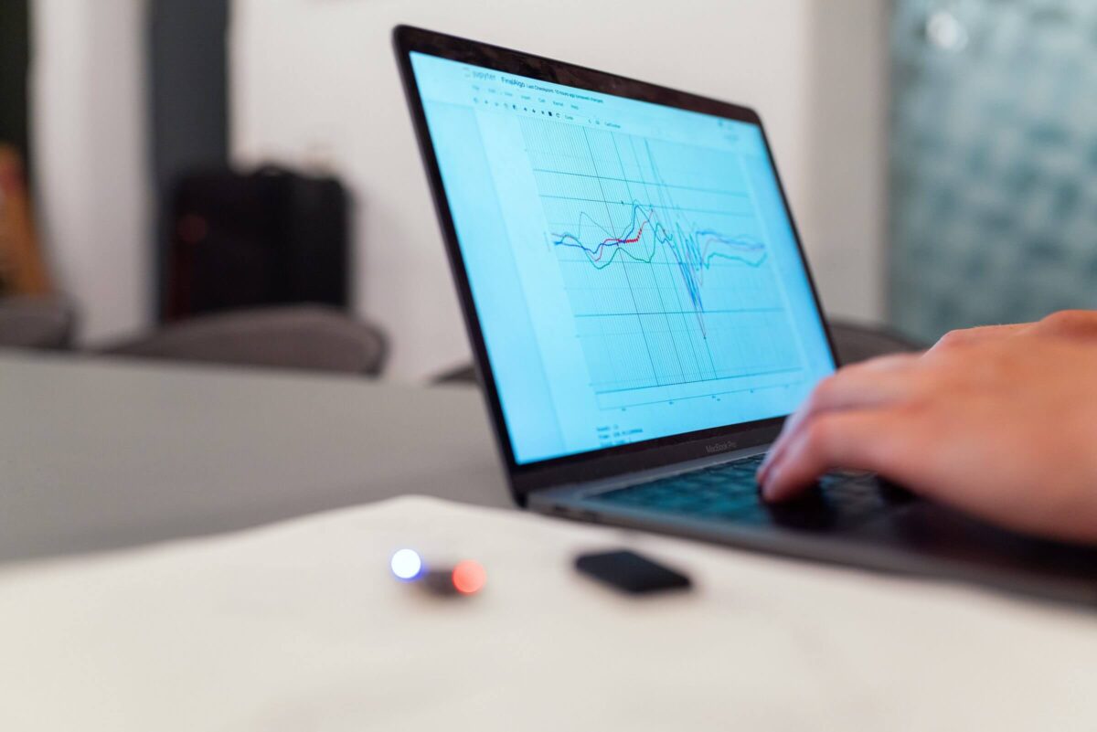 A person working on a laptop displaying a line graph with multiple colored lines.