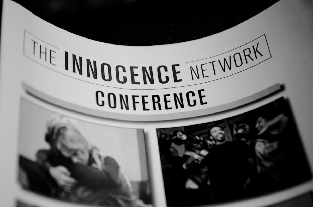 Black and white photo of a sign reading "The Innocence Network Conference" with small images below.